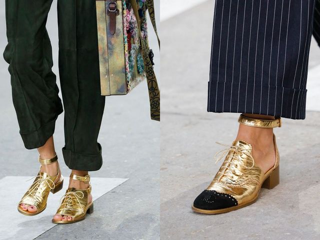 Close-up of a woman wearing gold metallic lace-up shoes with a black toe cap and a woman in gold strappy sandals