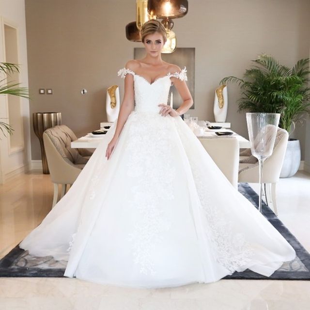 Woman in a white off-the-shoulder ball gown with lace detailing and a full skirt