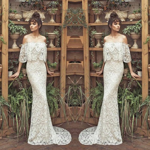 Woman in an off-the-shoulder white lace gown with a fitted silhouette and flowing sleeves