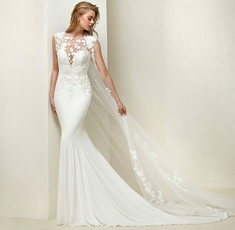 Woman in a white mermaid wedding gown with lace detailing and a sheer veil