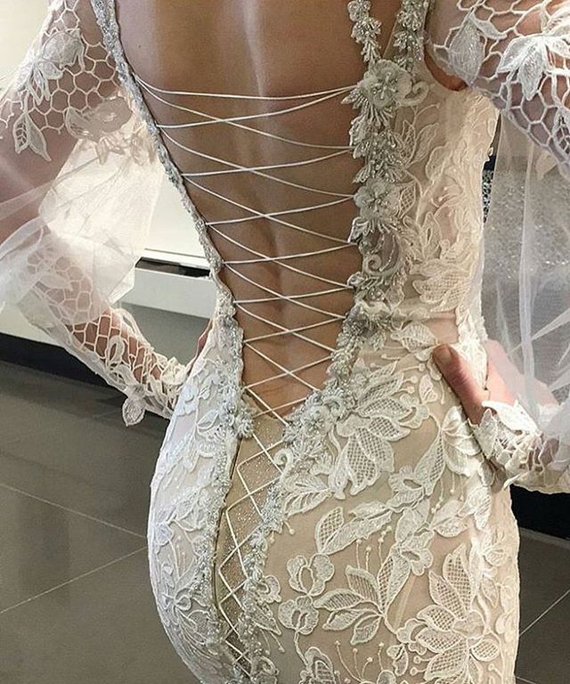Close-up of a woman in a white lace gown with a low back and sheer long sleeves
