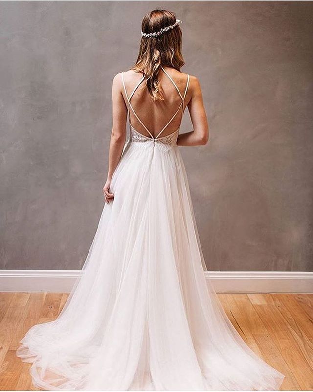 Woman in a white tulle gown with a low back and delicate spaghetti straps, wearing a silver headband