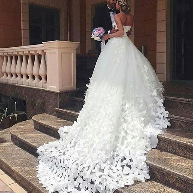 Woman in a white strapless wedding gown with a flowing skirt adorned with floral appliqués
