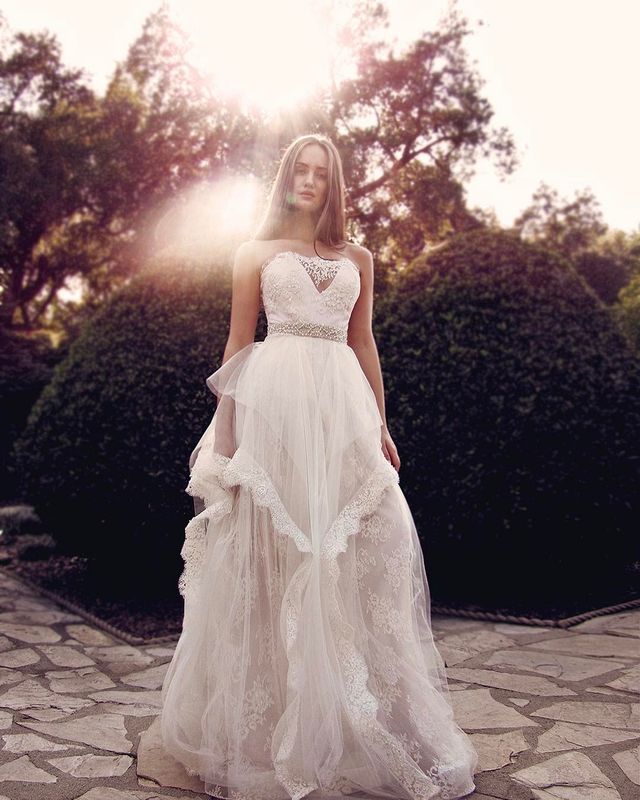 Woman in a white lace wedding gown with a sweetheart neckline and layered tulle skirt