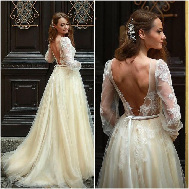 Woman in a cream lace long-sleeve gown with a deep back and flowing skirt