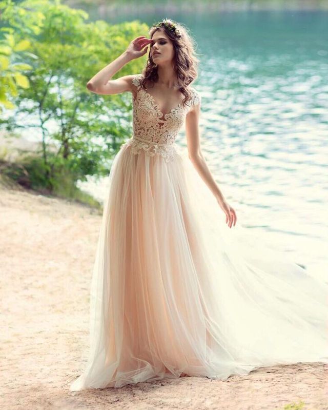 Woman in a blush tulle gown with lace detailing and a floral crown by a lake