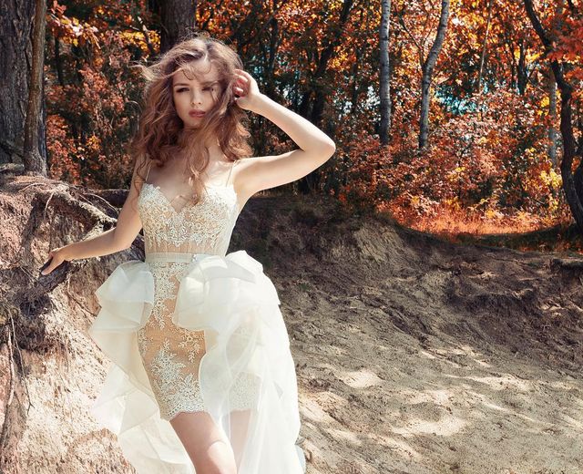 Woman in a white lace mini dress with a ruffled overlay and sheer skirt in a forest setting
