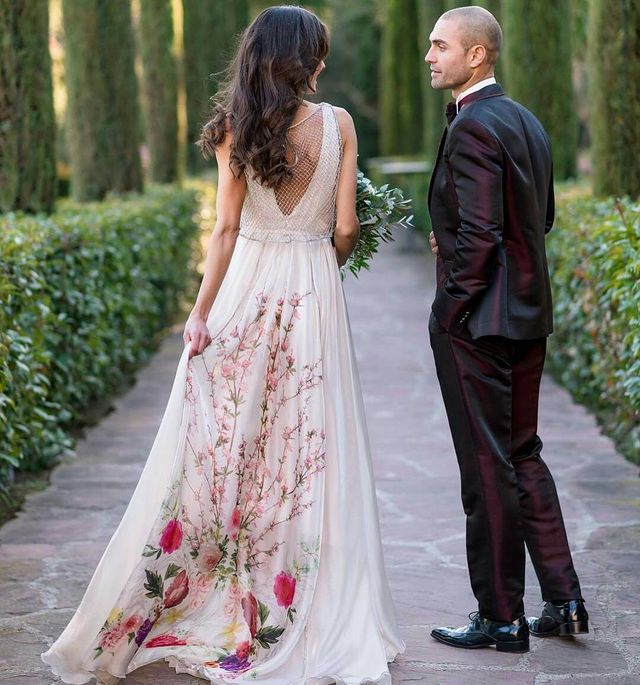 Woman in a white floral maxi dress with a sheer back and a man in a black tuxedo