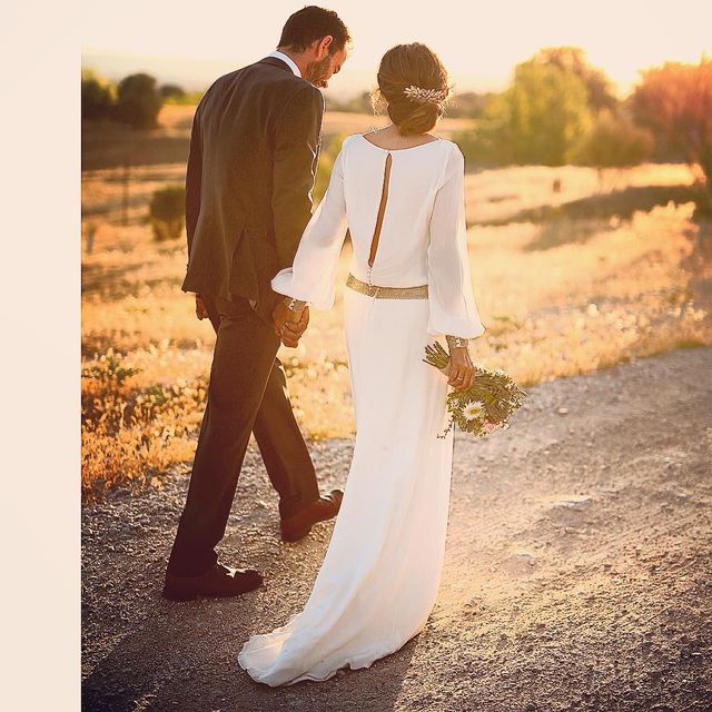 Woman in a white long-sleeve wedding dress with a keyhole back, holding a bouquet of flowers