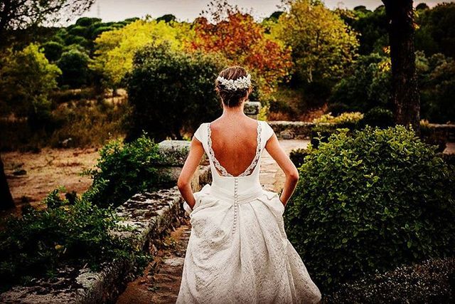 Woman in a white lace wedding dress with a low back and floral hair accessory in an outdoor setting