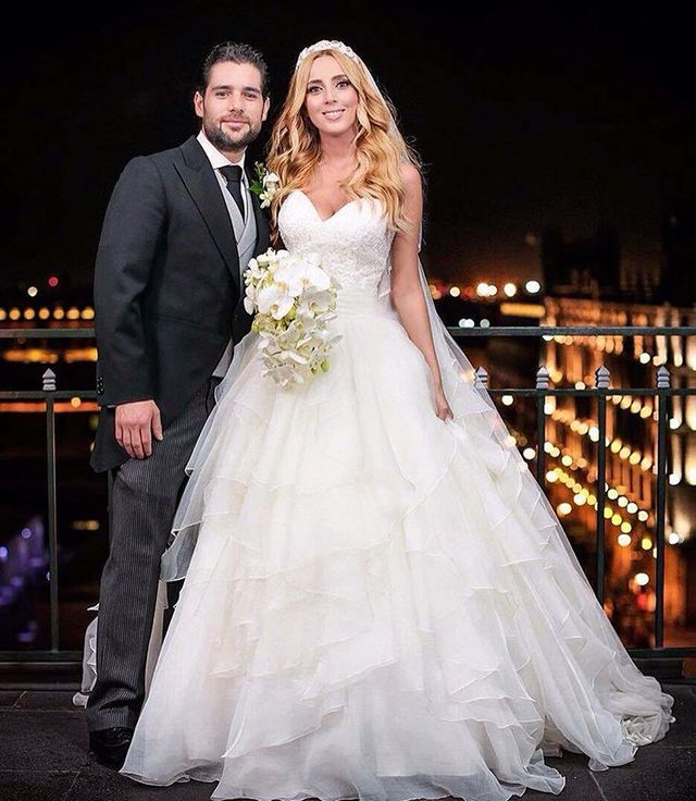 Woman in a white tiered wedding dress with a sweetheart neckline and a veil, holding a bouquet of white flowers