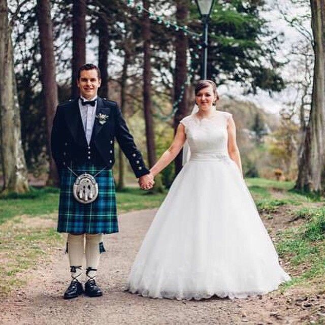 Woman in a white wedding dress and a man wearing a black tuxedo with a blue tartan kilt and sporran