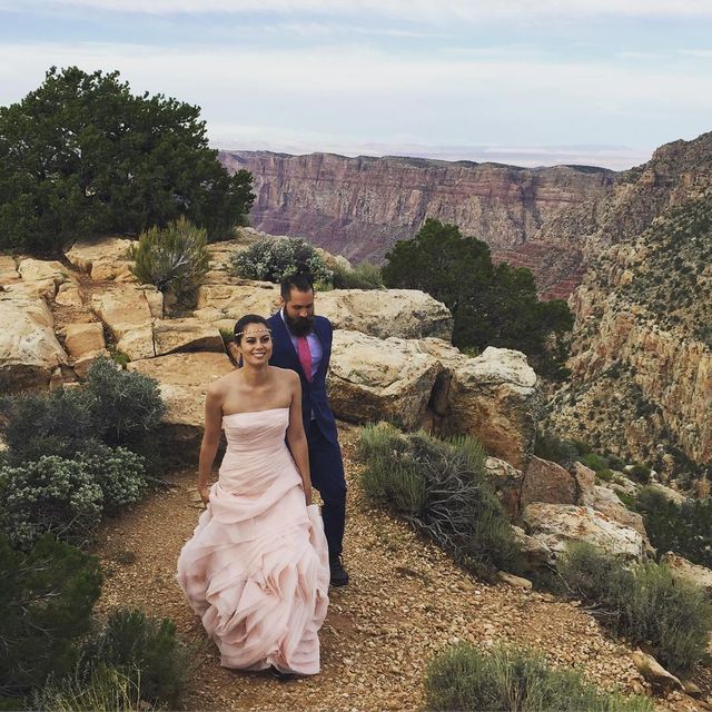 Woman in a light pink strapless gown with a full skirt walking on a rocky path with a man in a suit