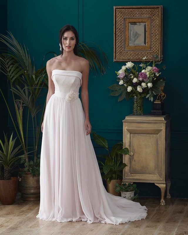 Woman in a strapless pale pink chiffon gown with a fitted bodice and flowing skirt