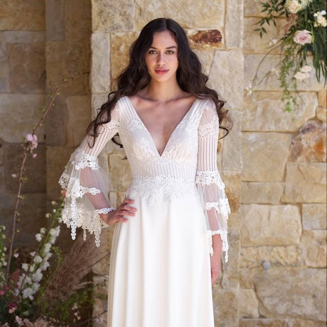 Woman in a white lace wedding dress with long sheer sleeves and a deep V-neckline