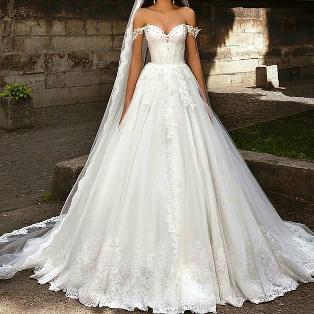 Woman in a white off-the-shoulder ball gown with lace detailing and a long veil