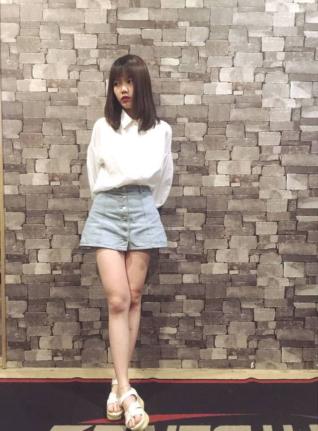 Woman wearing a white button-up shirt and a light blue denim mini skirt with white sandals