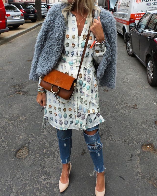 Woman wearing a light blue faux fur jacket, white printed dress with ruffles, distressed blue jeans, and nude pointed-toe heels, carrying a brown crossbody bag