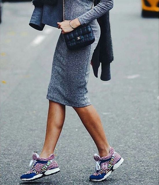 Woman in a grey fitted midi dress, carrying a black crossbody bag and wearing colorful patterned sneakers