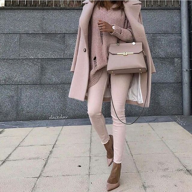Woman wearing a light pink oversized coat, matching sweater, and pale pink skinny jeans with nude pointed-toe heels and a beige handbag
